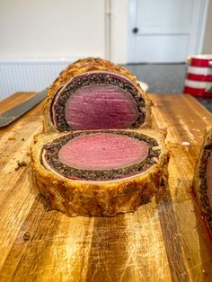 three pieces of meat sitting on top of a wooden cutting board