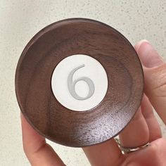 a close up of a person's hand holding a wooden object with the number six on it