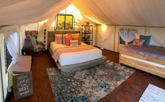 a bed sitting inside of a tent on top of a wooden floor next to two beds