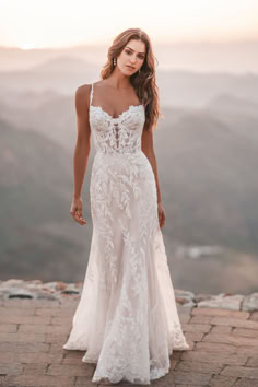 a woman in a wedding dress standing on top of a mountain