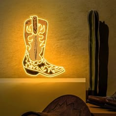 a cowboy boot is lit up on the wall next to a cactus and other items