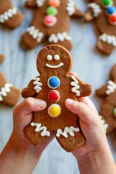 a person holding up a ginger cookie with candy on it