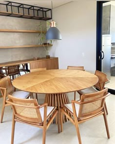 a round wooden table surrounded by chairs in a room with glass doors and shelves on the wall