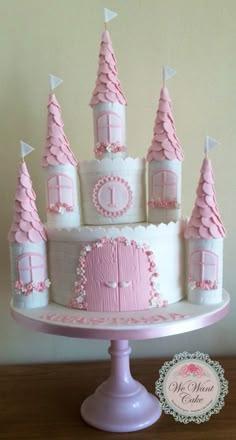 a pink and white castle cake on top of a table