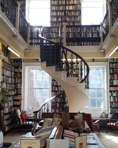 a spiral staircase in the middle of a library filled with books