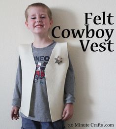 a young boy standing in front of a white wall wearing a vest and smiling at the camera