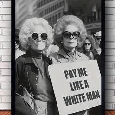 two women holding a sign that says pay me like a white man