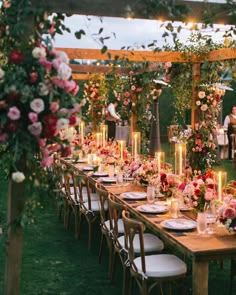 a long table is set with flowers and candles for an outdoor wedding reception in the evening