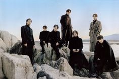 a group of people sitting on top of rocks next to each other near the ocean