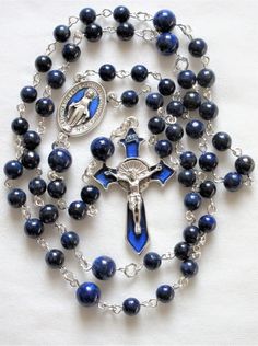 This lapis lazuli rosary can also be worn as a necklace. The body is about 27 inches and the cross extension is 6 inches. The blue enameled cross and connection were made in Italy and are oxidized silver. I used 6mm and 8mm lapis rounds and hand turned each of the wires myself. The crucifix is 1 and 3/4 inches long. This rosary will be slipped into an organza bag and shipped in a bubble mailer. Handmade Blue Crucifix Jewelry, First Communion Gifts, Catholic Rosary, Rosary Necklace, Communion Gifts, Rosary Catholic, Miraculous Medal, Bubble Mailer, Oxidized Silver