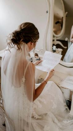 a bride is sitting in front of a mirror and writing on her wedding day note