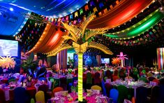 To create a Rio Carnival theme we dressed the ceiling with hundreds of metres of bunting, ribbon and flags, while on the ground, Brazilian dance troops with feathered headdresses and sequinned costumes paraded between a sea of brightly coloured tables which were dressed with a number of Carnival themed table centres. From illuminated LED palm trees and arrangements of bird of paradise and palms, to coloured candelabra and rotating ribbon chandeliers, guests were fully emerged in the theme. Island Carnival Theme Party, Rio Carnival Prom Theme, Rio Carnival Theme Party Decorations, Brazilian Carnival Theme Party, Brazil Carnival Theme Party, Rio Carnival Theme Party, Carnaval Decoration, Brazilian Party, Brazilian Dance