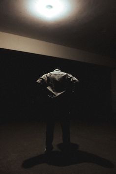 a person standing in the dark with their back turned to the camera