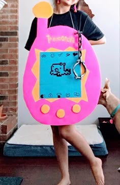 Girl standing with carboard cutout on as a tamagotchi costuem Tamagotchi Costume, Toy Costumes, 5k Costume, October Month, Best Group Halloween Costumes, Duck Costumes, Hawaii Dress