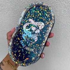 a person holding up a blue case with glitters on it and a skull in the middle