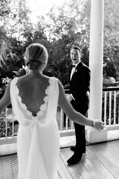 a bride and groom holding hands on the porch