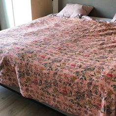 a bed with a pink bedspread on top of it in a bedroom next to a window