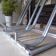 two metal chairs sitting next to each other on a tiled floor in front of a potted plant