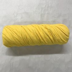 a spool of yellow thread on a white surface