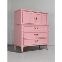 a pink dresser with gold handles and drawers