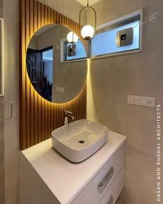 a bathroom sink sitting under a round mirror in front of a wall mounted faucet