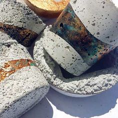 four cement cups and saucers sitting on top of a white plate with rusted edges