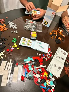 two people sitting at a table with legos on the table and one person holding a piece of paper