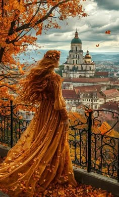 a woman in an orange dress is looking out over the city and trees with leaves on them