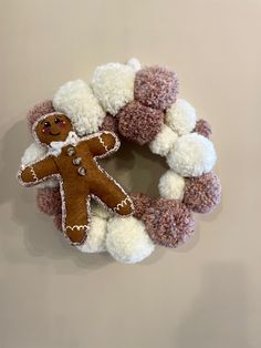 a gingerbread man wreath with pom - poms on the front and bottom