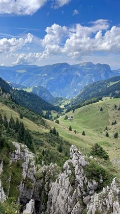 the mountains are covered in green grass and trees, with some rocks on each side