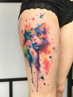 a woman's thigh with a colorful cat tattoo on her leg and the bottom part of her thighs