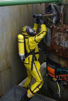 a man in yellow and black suit working on pipes