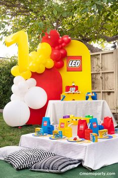 a table with legos and balloons on it in front of a large balloon arch