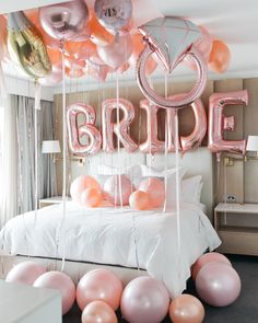 balloons are hanging from the ceiling in front of a bed with pink and silver decorations