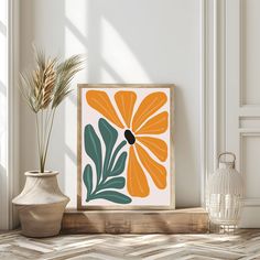 an orange and green flower on a white wall next to two vases with plants