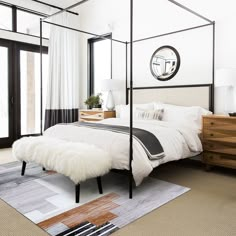 a bedroom with a four poster bed and white walls