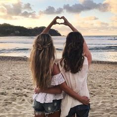 two girls making a heart shape with their hands on the beach, saying what do you want for your best friend?