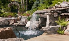 an outdoor hot tub with waterfall and rocks