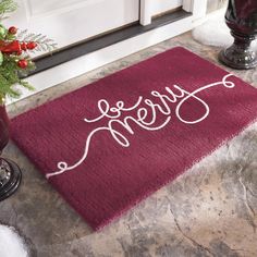 a red door mat with the word home on it next to a potted plant