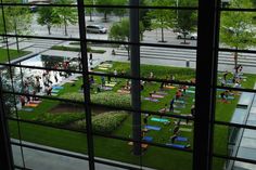 people are doing yoga outside in the grass near some trees and bushes, as seen through large windows