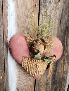 a heart shaped pillow with dried flowers in it sitting on a wooden surface next to a wall