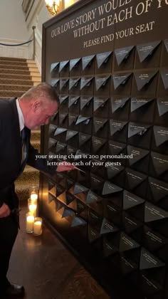 a man in a suit and tie standing next to a wall with candles on it