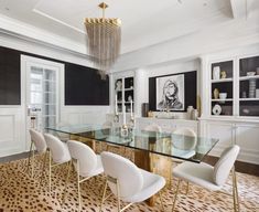 a dining room table with white chairs and a chandelier