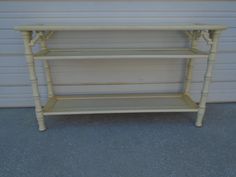 a yellow shelf with three shelves on it in front of a garage door and wall