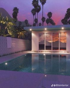 an empty swimming pool at dusk with palm trees in the background and lights shining on it