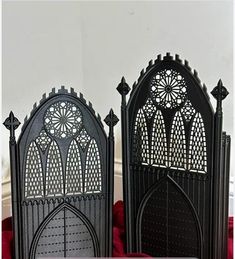 two black iron gothic style bookends sitting on top of a table