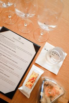 a table with wine glasses, menu and other items sitting on top of the table