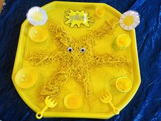 a yellow plate with noodles and plastic utensils on it that have googly eyes