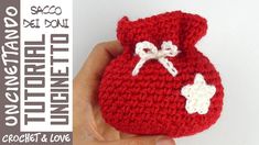 a hand holding a crocheted red bag with white bows on the front and bottom