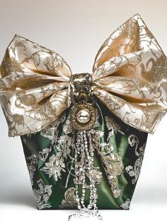 a green and gold purse with a large bow